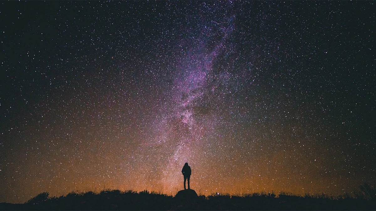 A man staring at a night sky full of stars demonstrating that the sky is the limit.
